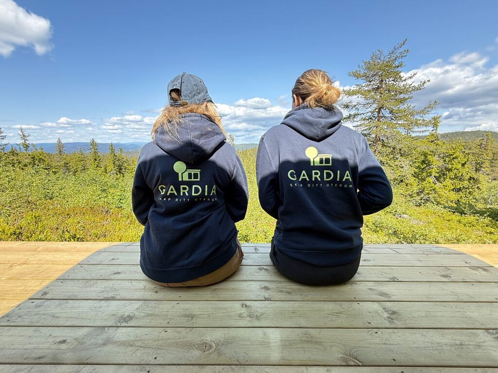 to damer sitter på platting med hettejakker med logo