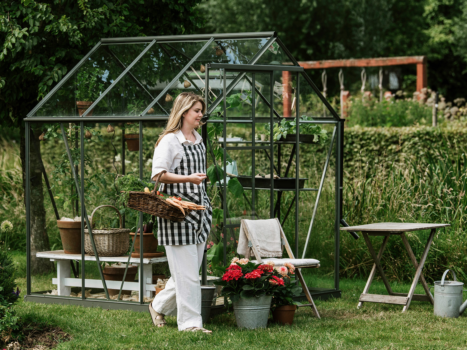 dame med kurv foran grønt drivhus